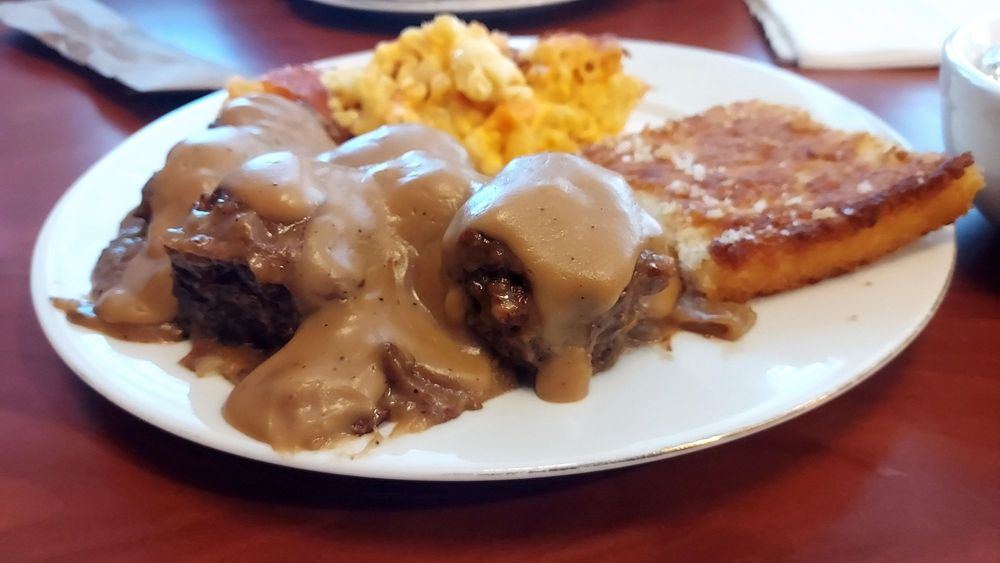 Hamburger steak smothered in gravy with macaroni and cheese and cornbread